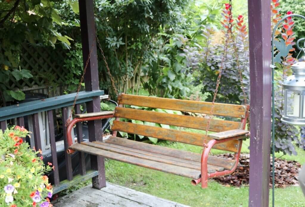 A wooden porch swing adds a touch of whimsy to any outdoor landscape! 